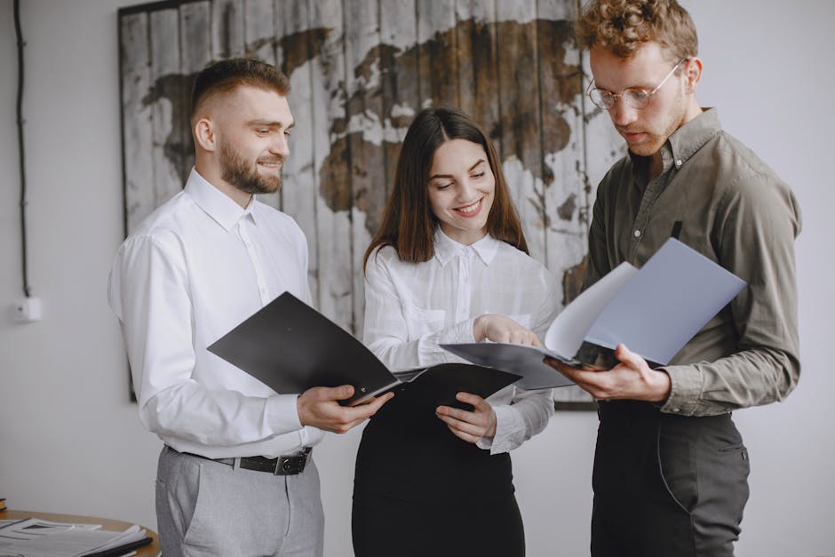 Three young professionals collaborating in an office, reviewing documents together.