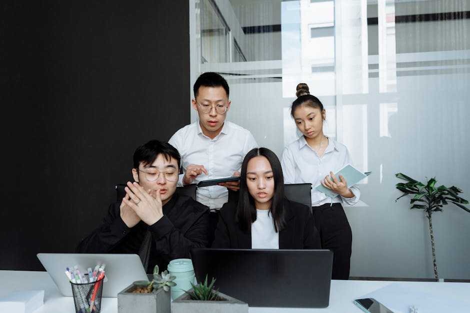 A diverse business team collaborates on projects in a modern office setting.