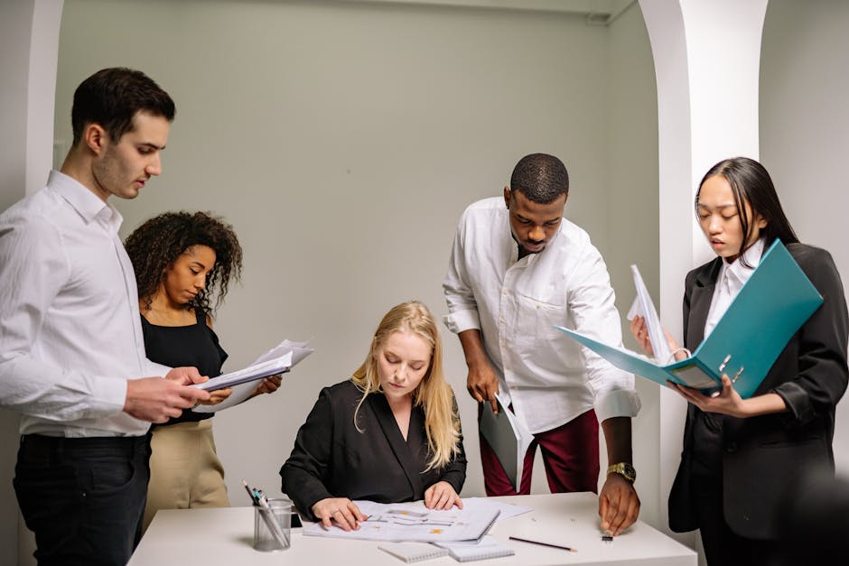 Diverse team working together in an office setting, reviewing documents and collaborating.