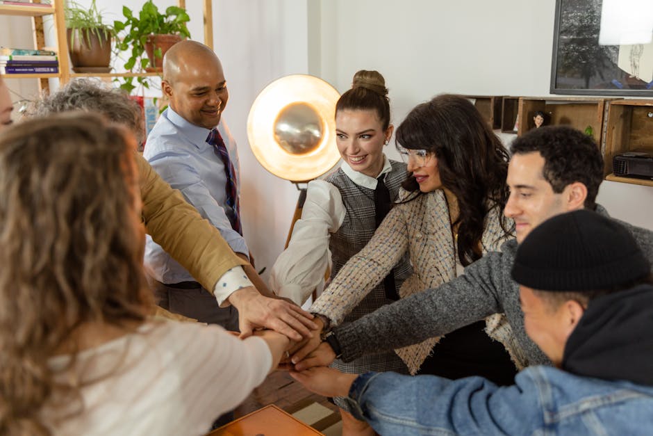A group of diverse coworkers engage in a team huddle in a contemporary office environment.