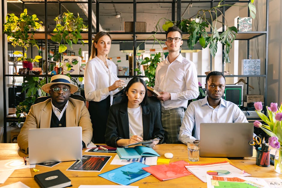 A diverse group of business professionals working together in a modern, plant-filled office space.